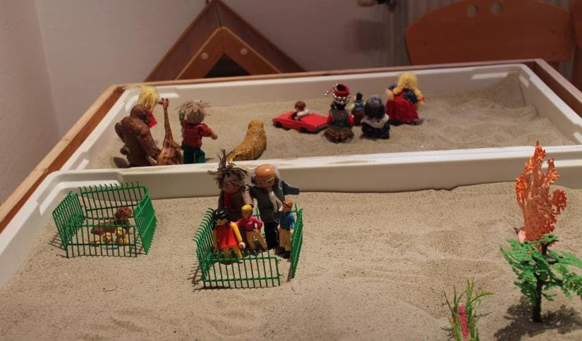 Små legetøjsfigurerer i sandkasse. Brugs til legeterapi for børn